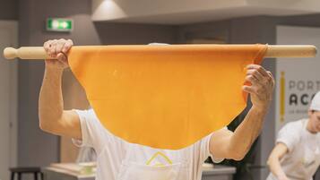 A person holding a large orange sheet above their head in a kitchen setting.