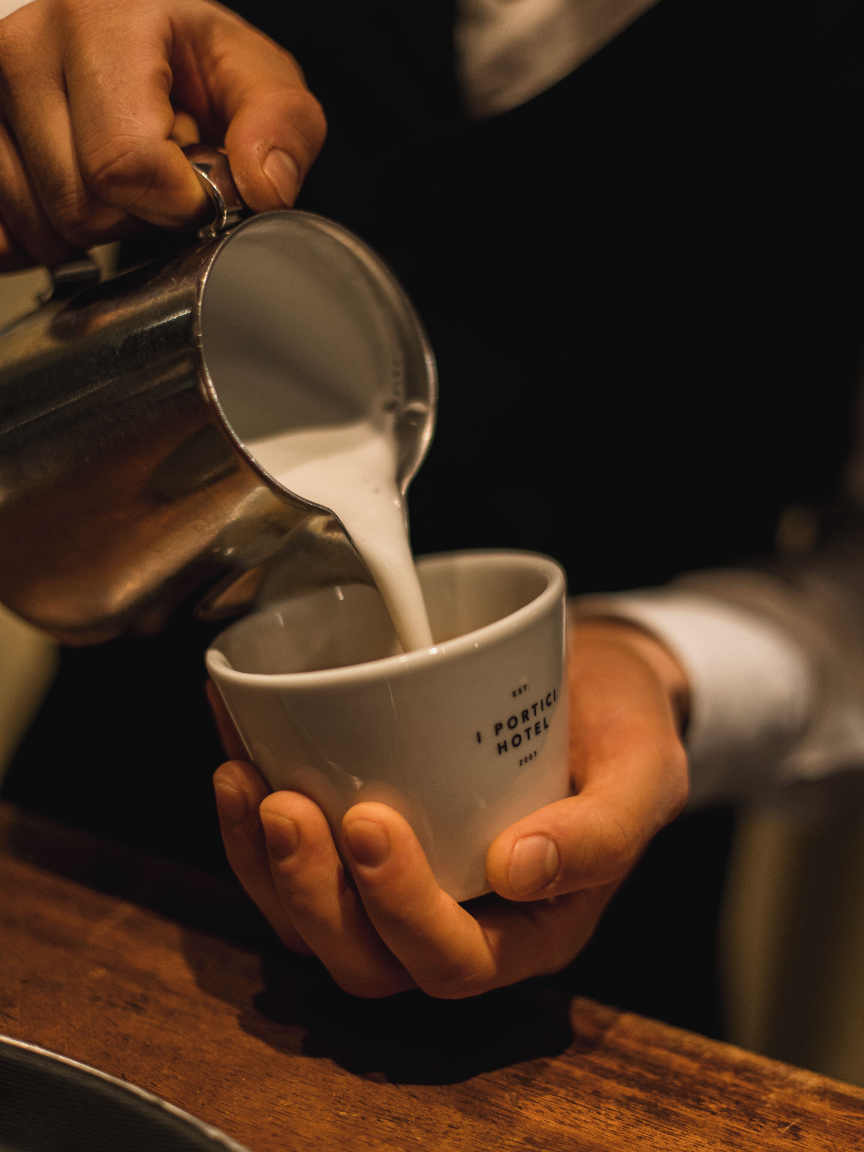 Eine Person gießt Milch in eine Tasse mit Aufdruck.