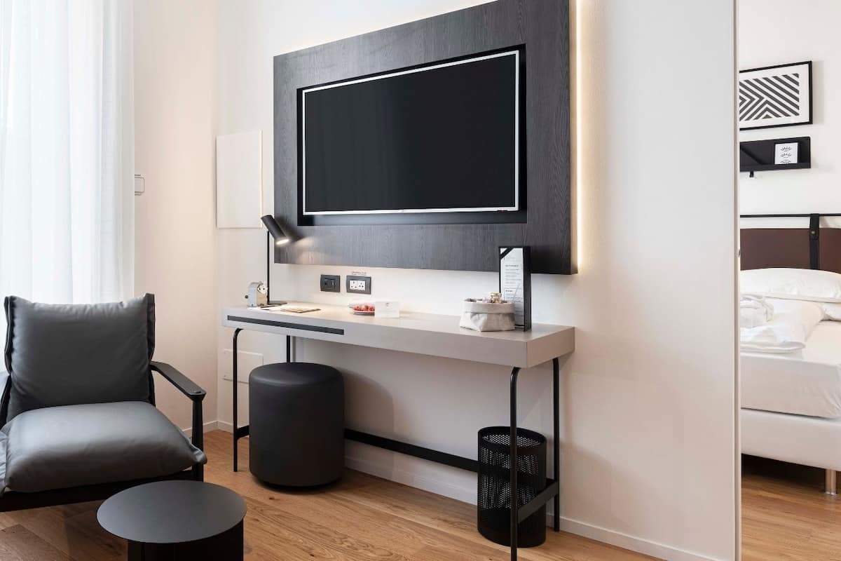 Moderni hotellihuone, jossa on työpöytä, tuoli ja sänky.