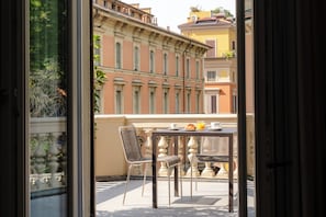 A balcony with a table and chairs, overlooking a building with classical architecture. - I Portici Hotel (Bologna)