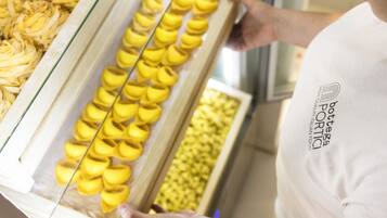 A person holding a tray with yellow pastries, possibly cannoli, in a bakery setting.