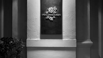 A black and white photo of a hotel entrance with a sign reading "I Portici Hotel Bologna" and steps leading up to it.