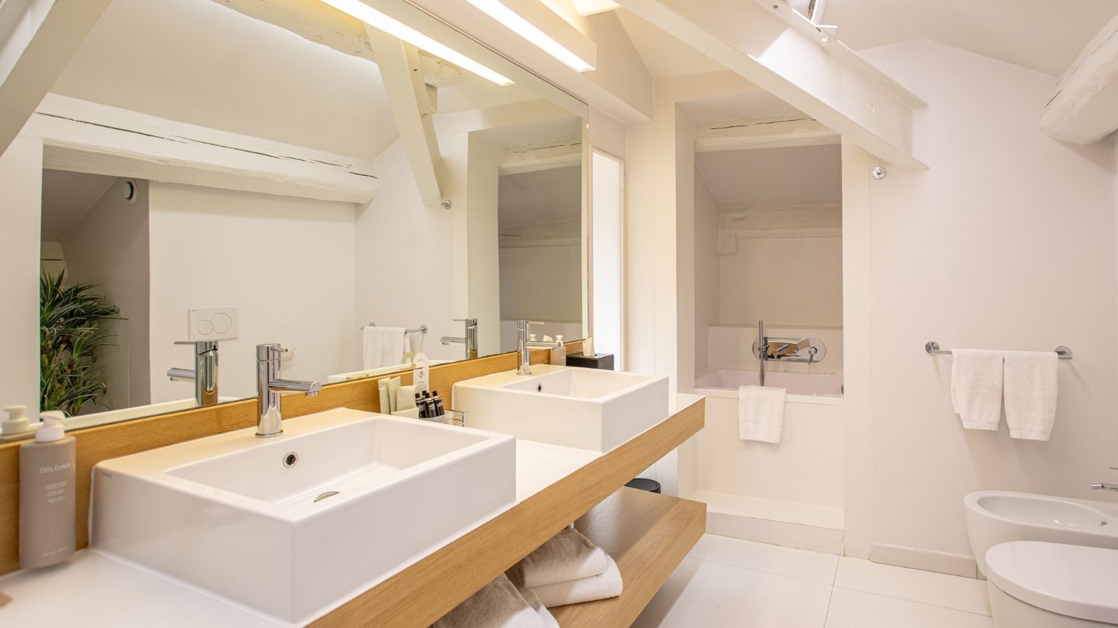 Un bagno moderno con due lavandini, uno specchio grande e una zona doccia.