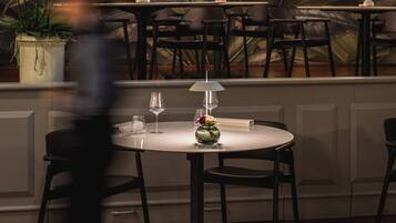 Ein Restaurantinneres mit runden Tischen, Stühlen und einem Wandbild mit tropischer Vegetation und dem Wort 'Eden'.