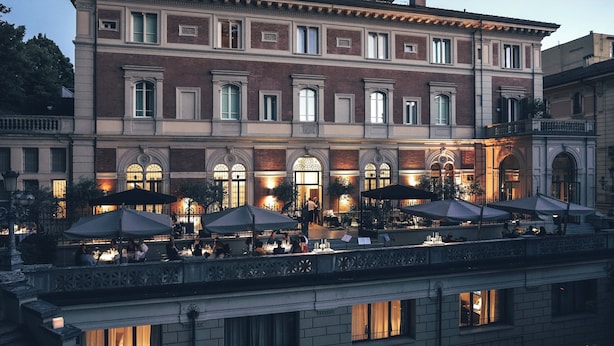 Un edificio histórico con un café en terraza, que ofrece asientos al aire libre y vistas a un canal.