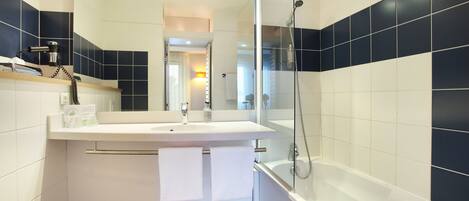 A modern bathroom with a white sink, mirror, and bathtub.
