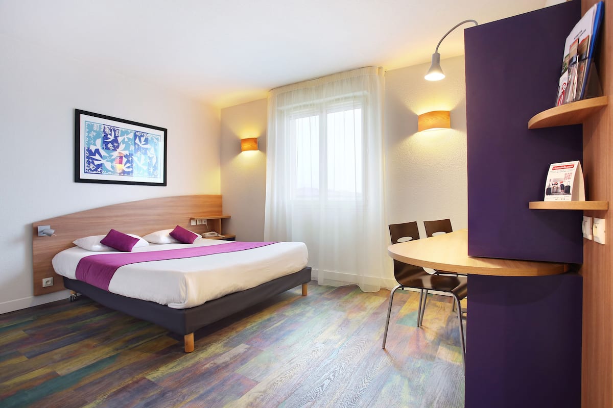 A hotel room with a bed, a desk, and a chair.