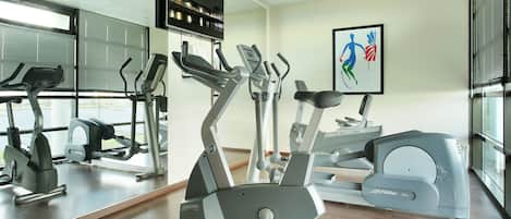 A gym with cardio machines, a mirror, and a motivational artwork on the wall.