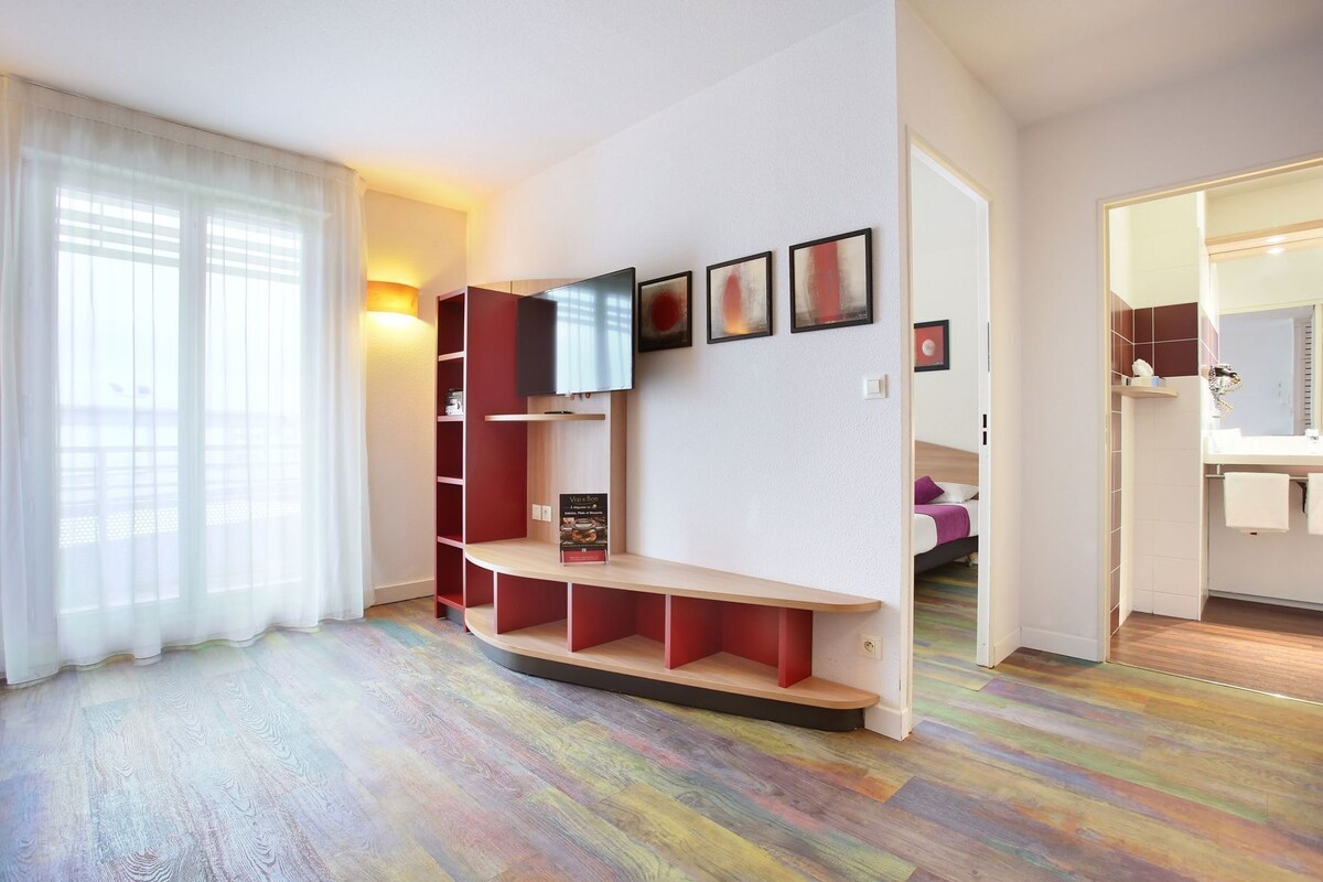 Una habitación moderna con una estantería curva, un televisor y obras de arte en la pared.