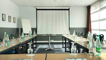A conference room with a long table, chairs, a projector screen, and water bottles.