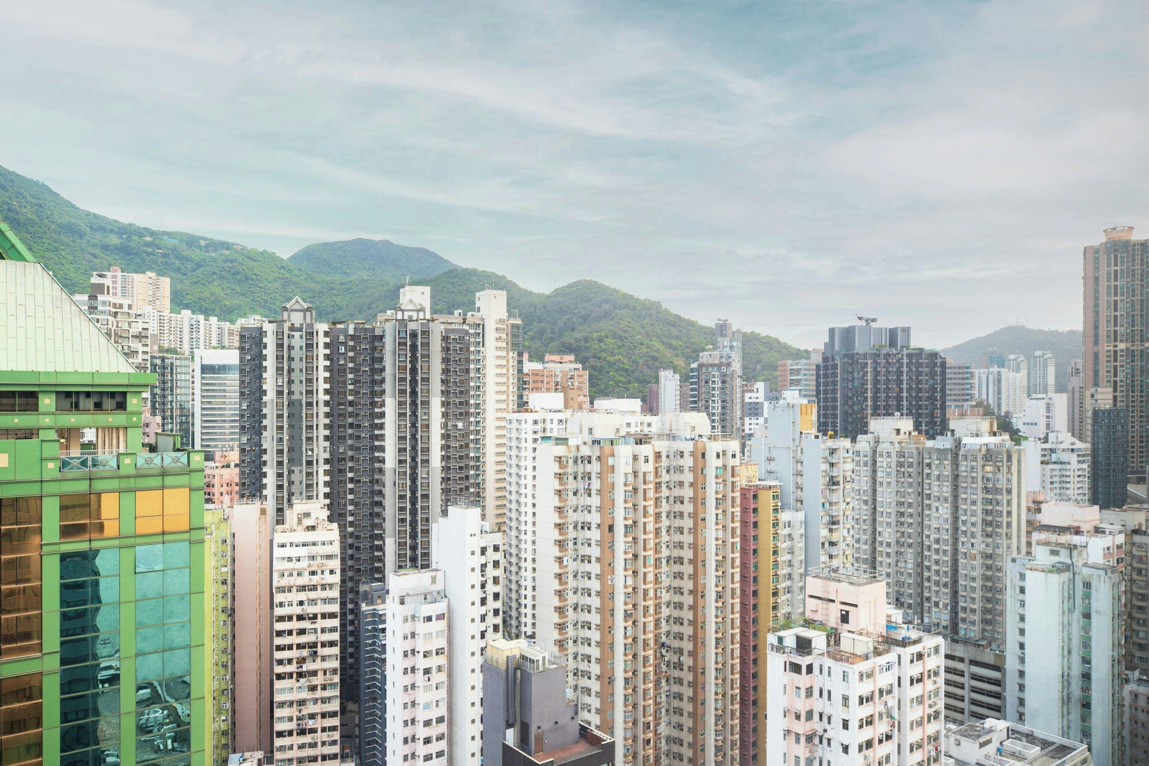 Un quartier urbain dense, composé de nombreux immeubles, dont certains présentent des balcons et des fenêtres apparents, avec un paysage montagneux en arrière-plan.