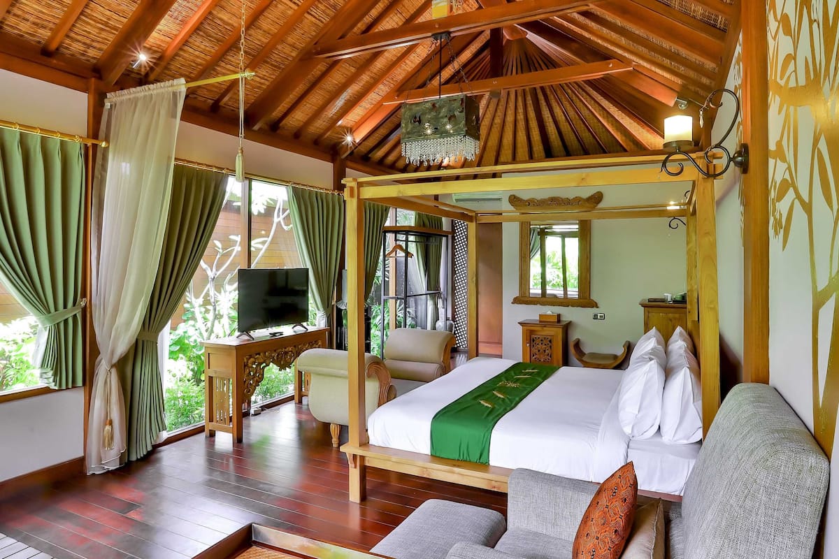 A spacious bedroom with a large bed, a television, and a wooden ceiling.