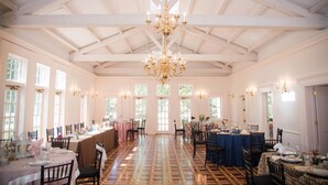 A spacious hall with high ceilings, chandeliers, and large windows. Tables are set for dining, and the floor has a patterned design. - The Bykenhulle House (Hopewell Junction)