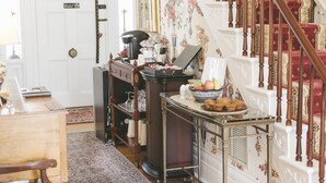 A staircase with red carpeted steps and wooden balusters, leading to a landing area with a table set with food and a coffee machine. - The Bykenhulle House (Hopewell Junction)