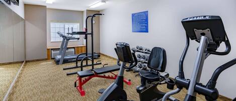 Ein Fitnessraum eines Hotels mit verschiedenen Trainingsgeräten, darunter Laufbänder, ein Crosstrainer und Kurzhanteln.