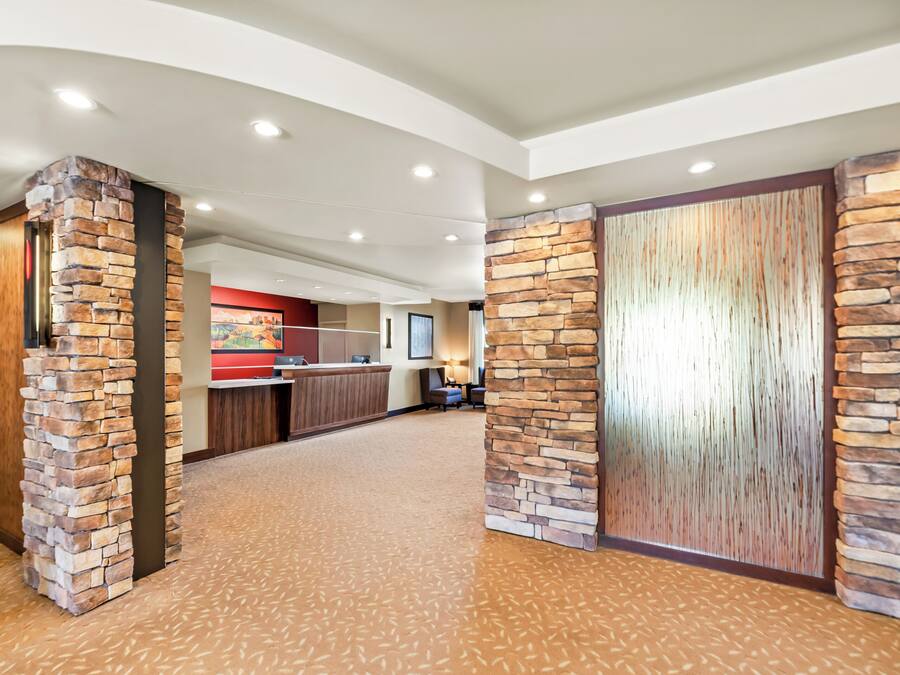 A hotel lobby with stone pillars, a reception desk, and a carpeted floor.