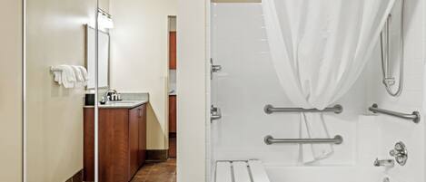 Un baño moderno con cabina de ducha de vidrio, una bañera blanca y un mueble de tocador de madera.