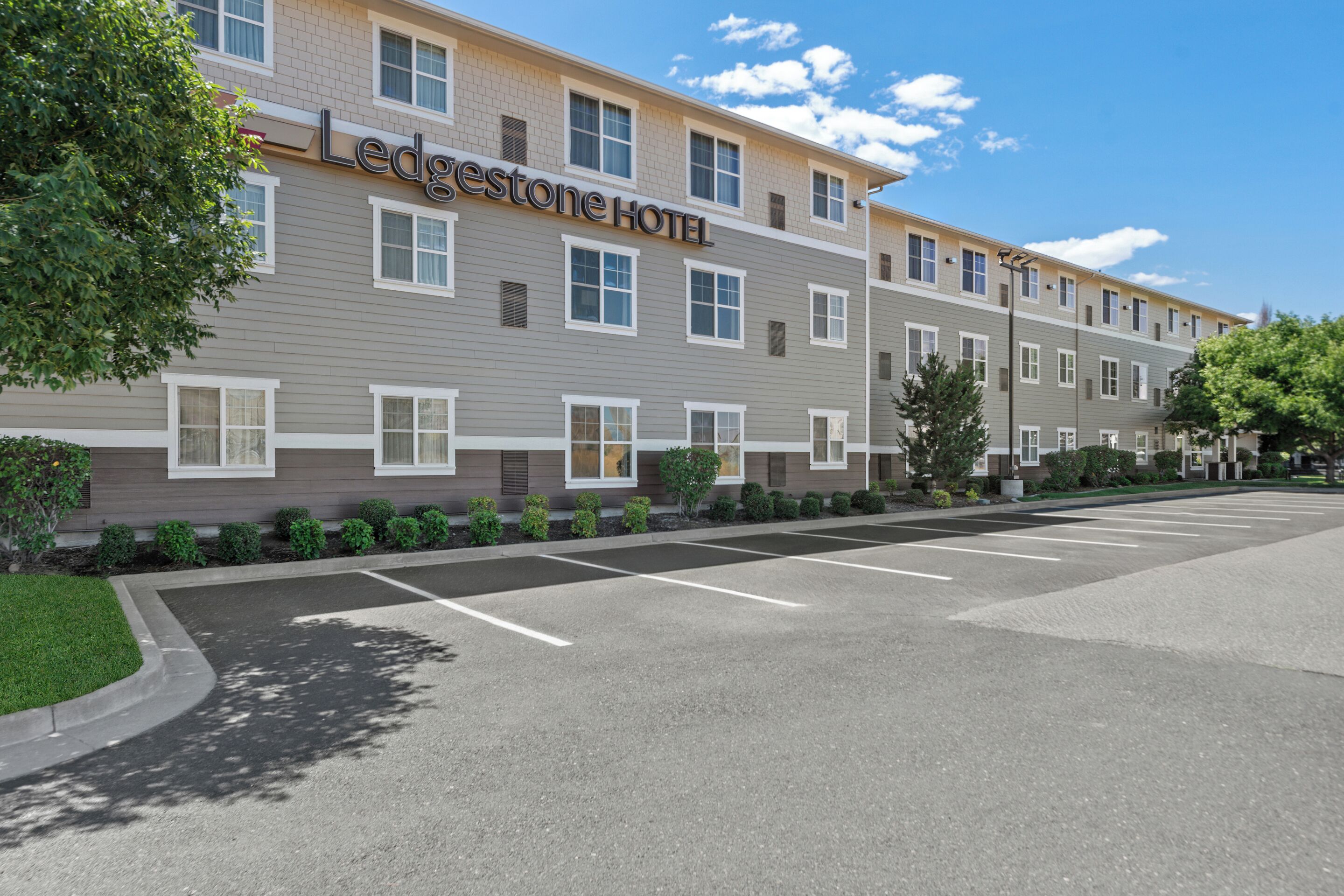 A multi-story hotel with a modern design, featuring a parking lot and well-maintained landscaping.