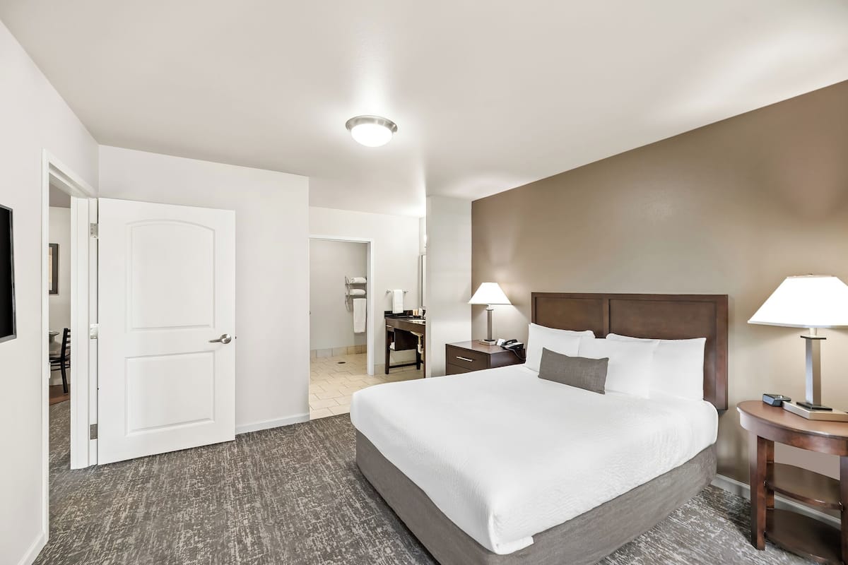 A hotel room with a large bed, two bedside tables with lamps, a desk, and a chair.
