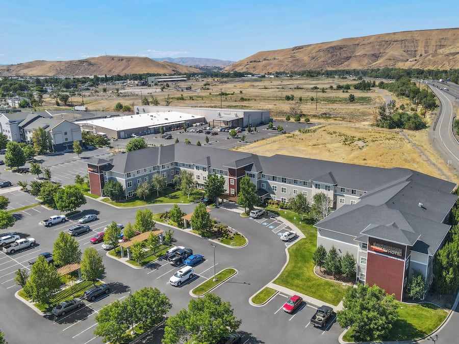 A hotel with a parking lot, multiple buildings, and a mountainous backdrop.