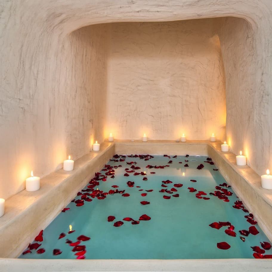 A spa bath with candles and rose petals.