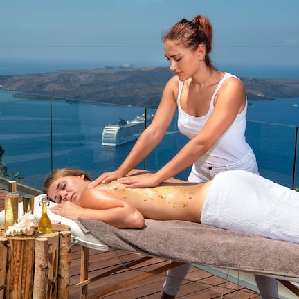 A massage therapy session on a wooden deck with a scenic ocean view.