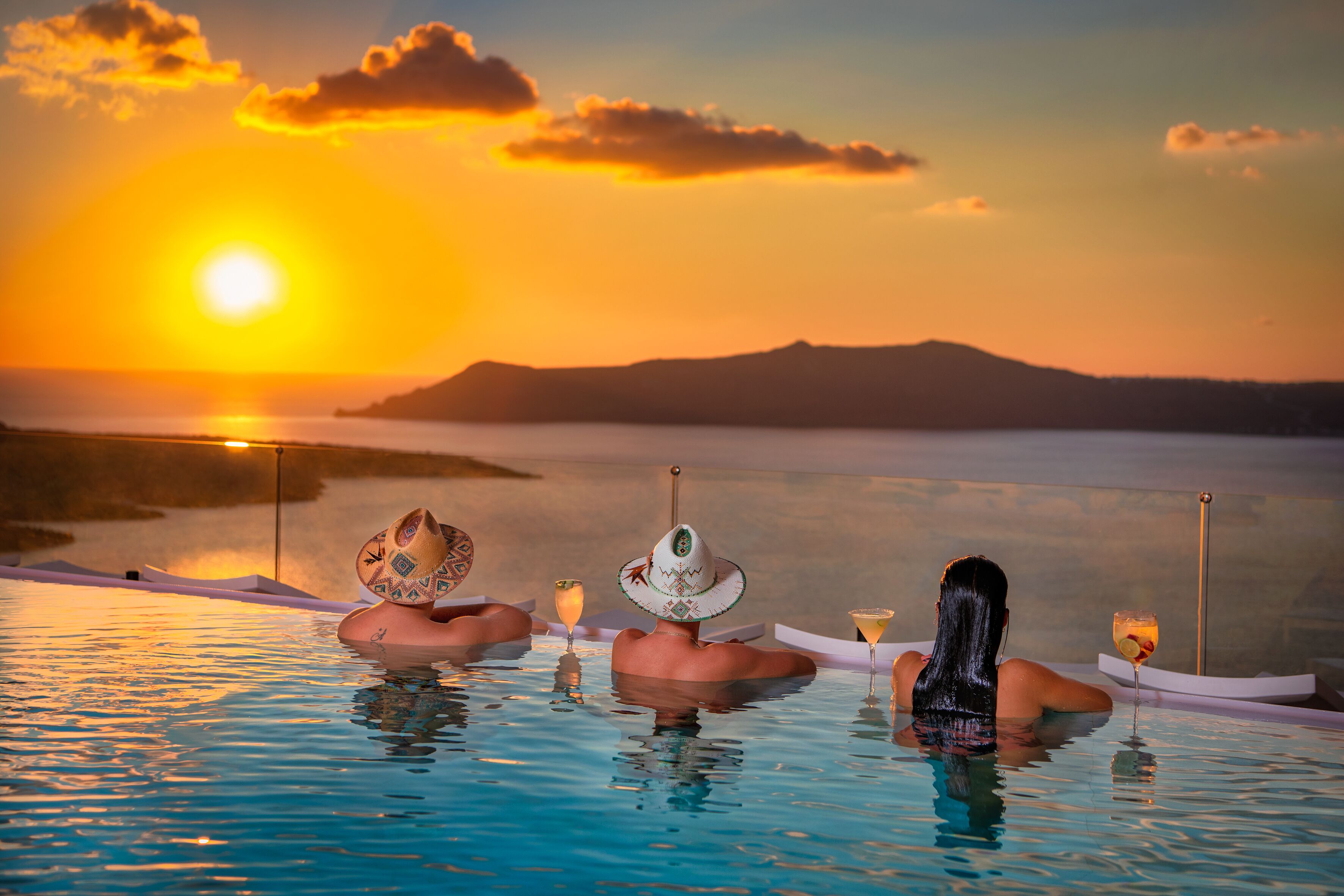 Una pareja relajándose en una piscina infinita privada con vista al atardecer.