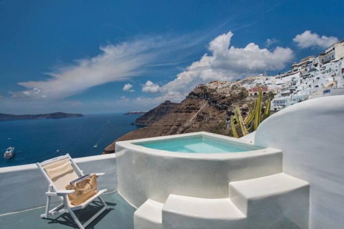 Un jacuzzi en una terraza con vista al mar y edificios blancos.