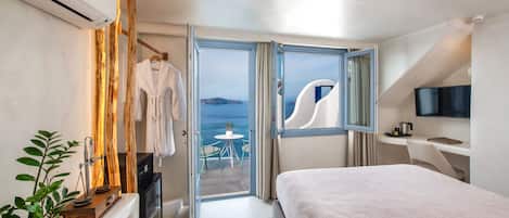 Een moderne hotelkamer met balkon, een bed, een televisie en een bureau.