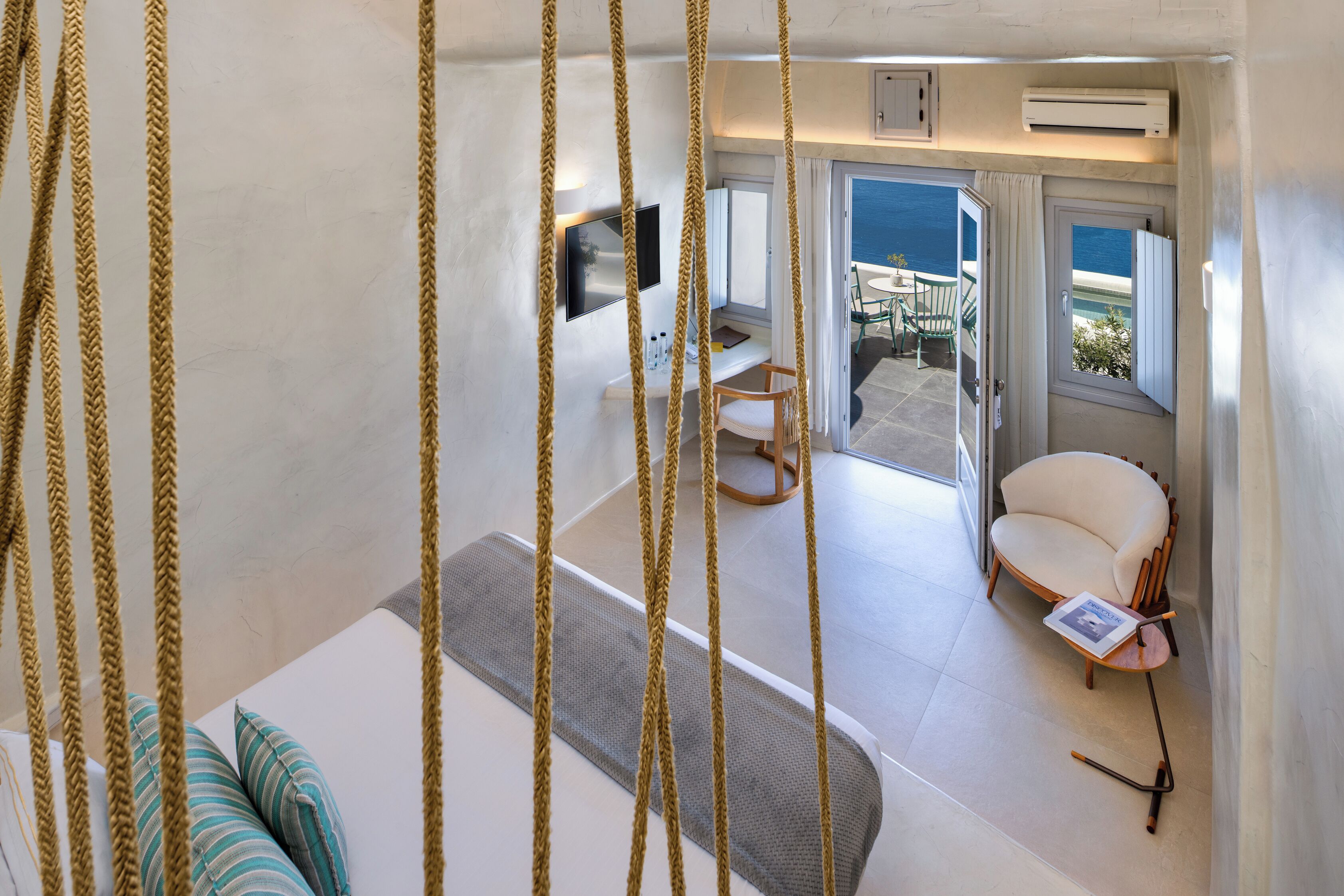 Una habitación con cama, escritorio, silla, televisión y vistas al exterior.