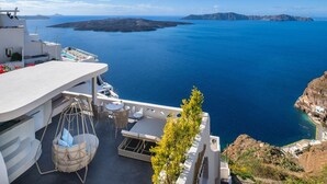 Una terraza con vistas al mar, mobiliario exterior y una silla colgante.