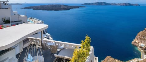 A terrace with a view of the sea, outdoor seating, and a hanging chair.