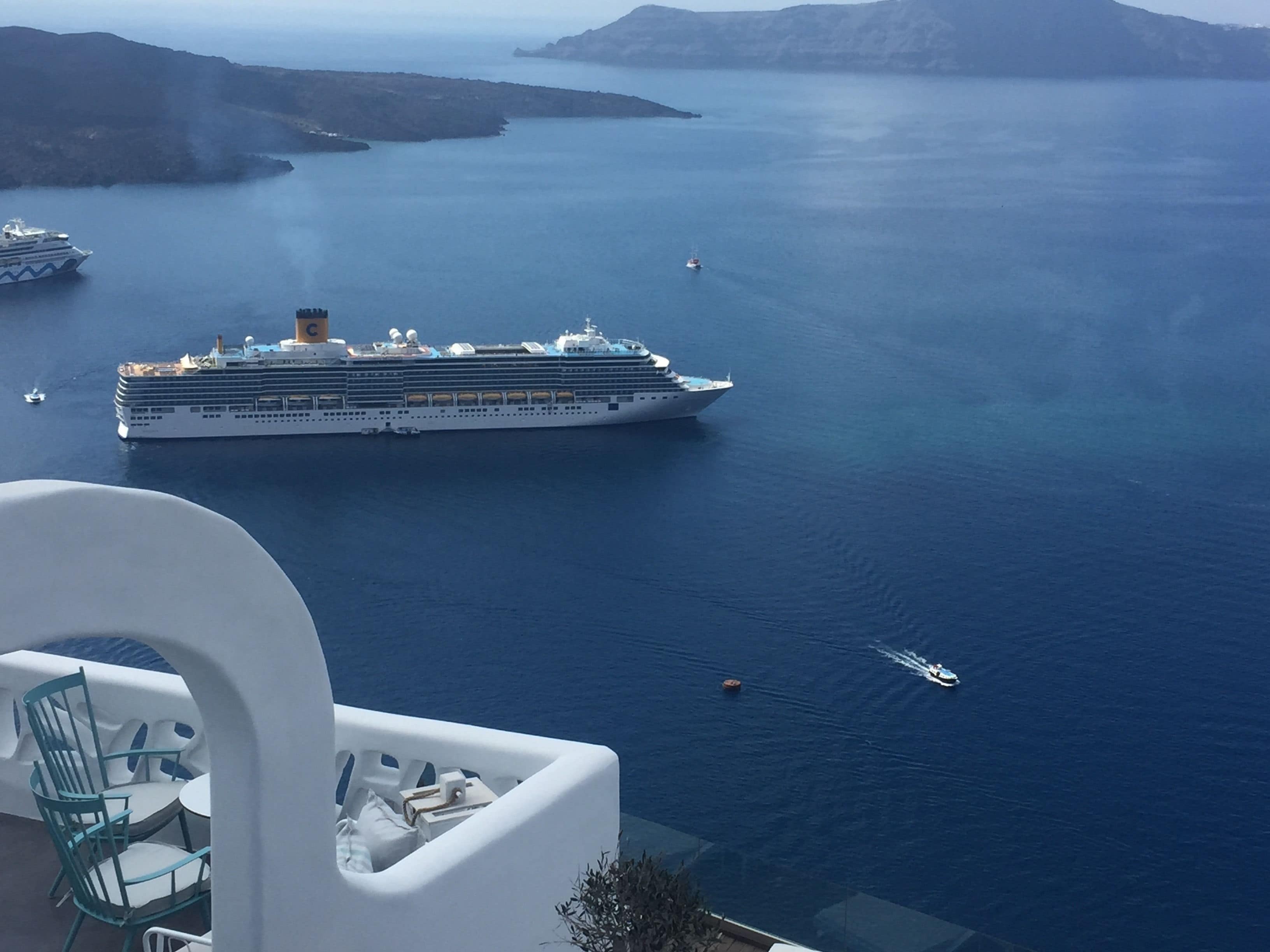 A large cruise ship in a calm sea with a clear view of the surrounding landscape.