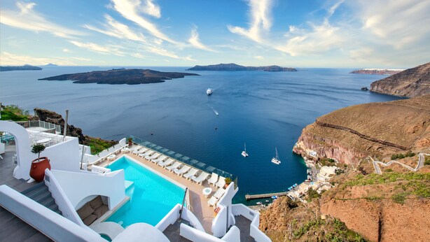 Un resort con piscina, sillas de descanso y vistas al mar y a las islas.