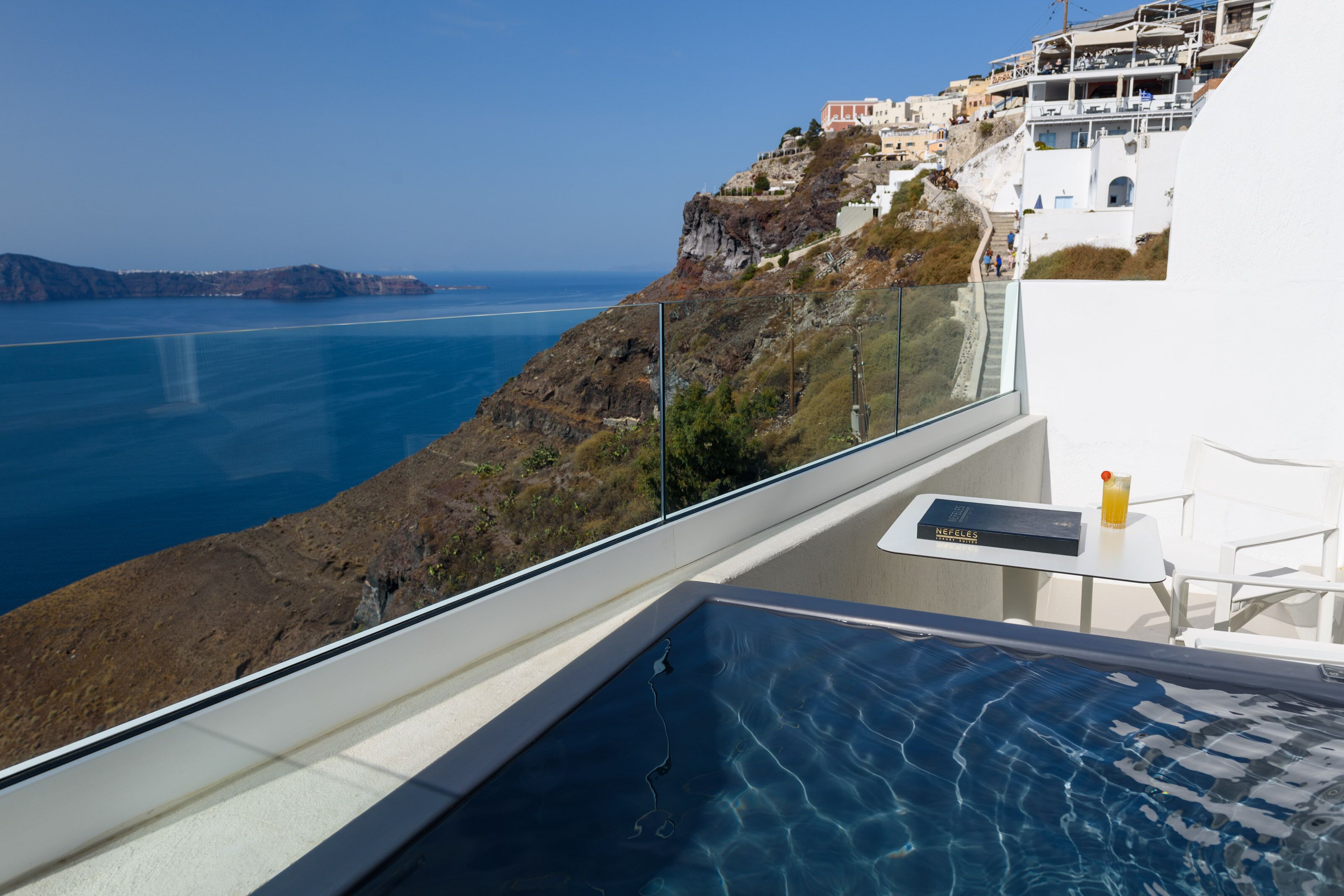 A balcony with a pool overlooking a coastal landscape.