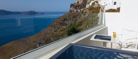 A balcony with a pool overlooking a coastal landscape.