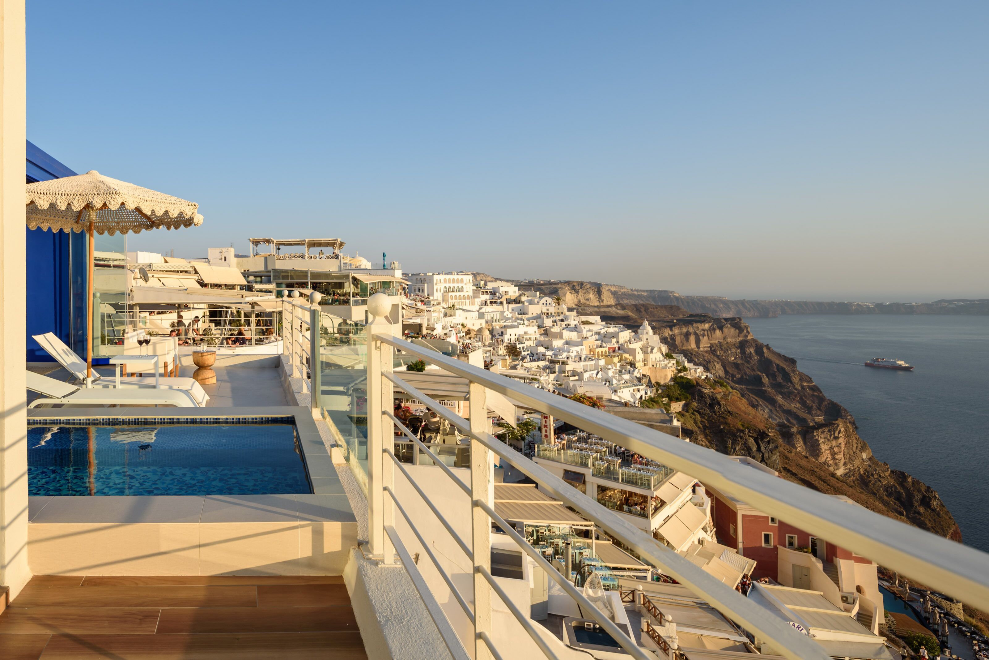 A rooftop pool with a view of a coastal town and cliffs.