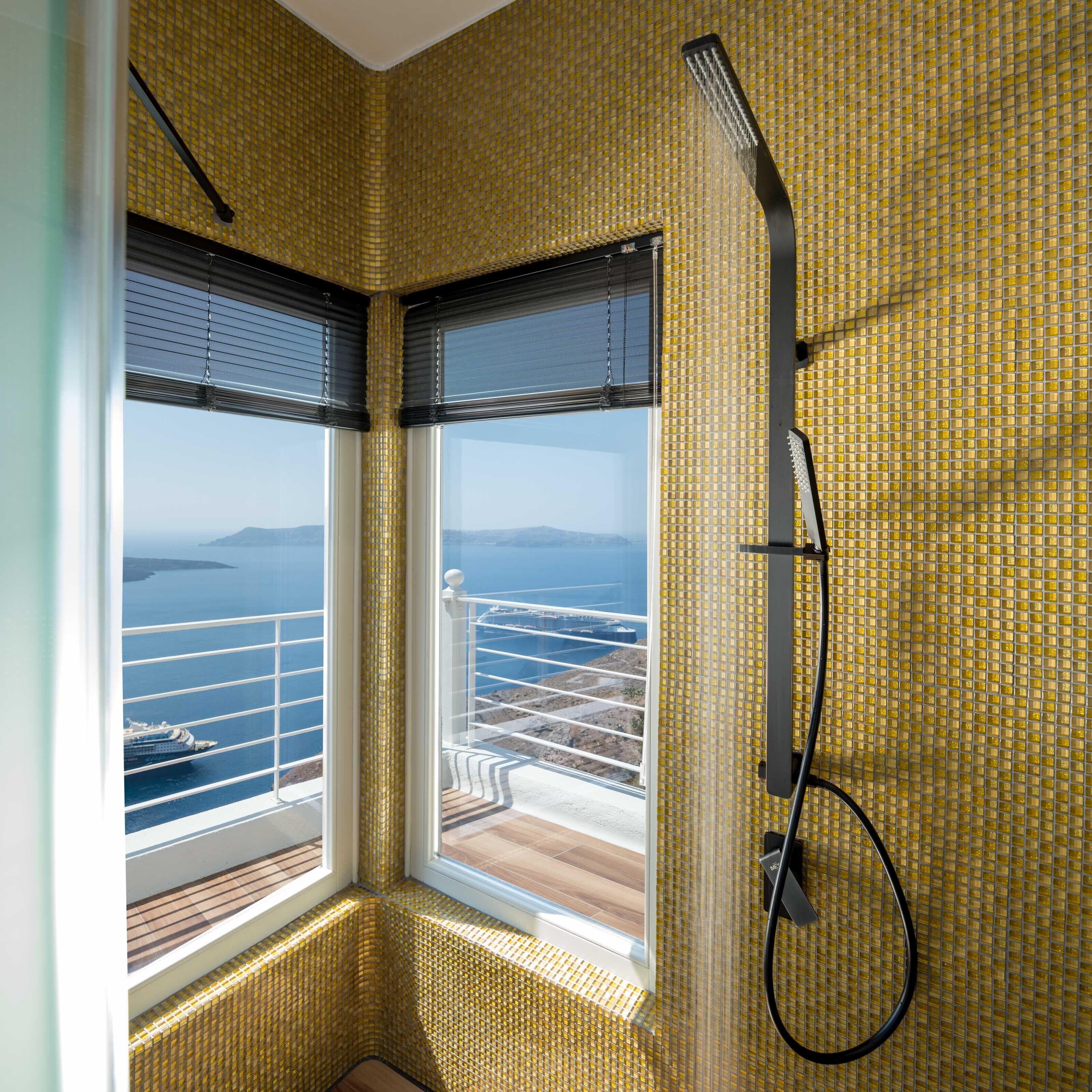 Ein Badezimmer im Eckbereich mit einem großen Fenster und Blick auf das Meer und ein Schiff.