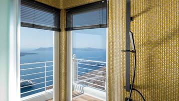 Ein Badezimmer im Eckbereich mit einem großen Fenster und Blick auf das Meer und ein Schiff.