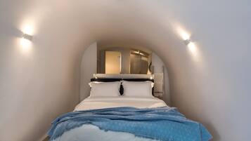 Un dormitorio con cama, cabecera y lámpara en el techo.