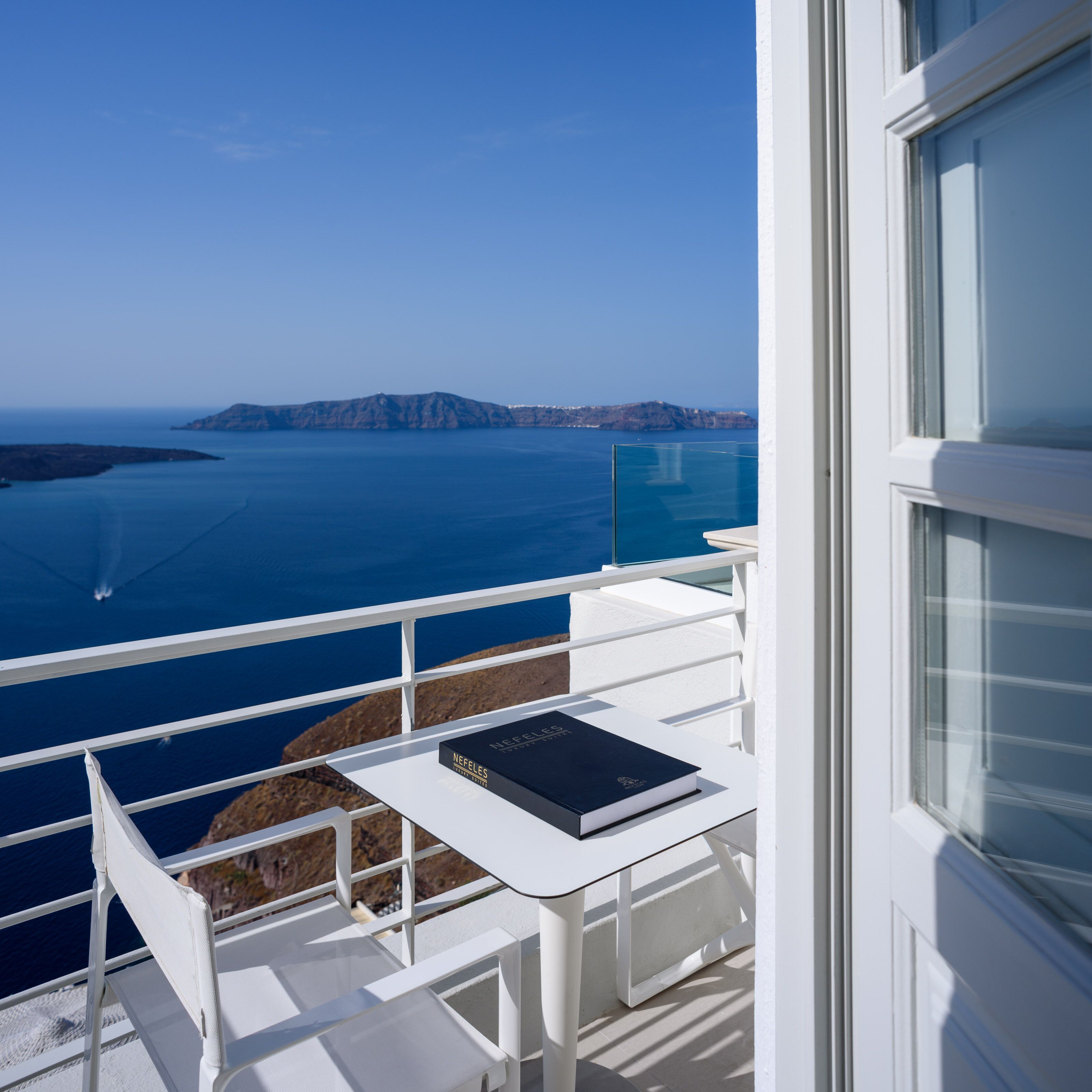 A balcony with a white table and a book titled "NEFELES".