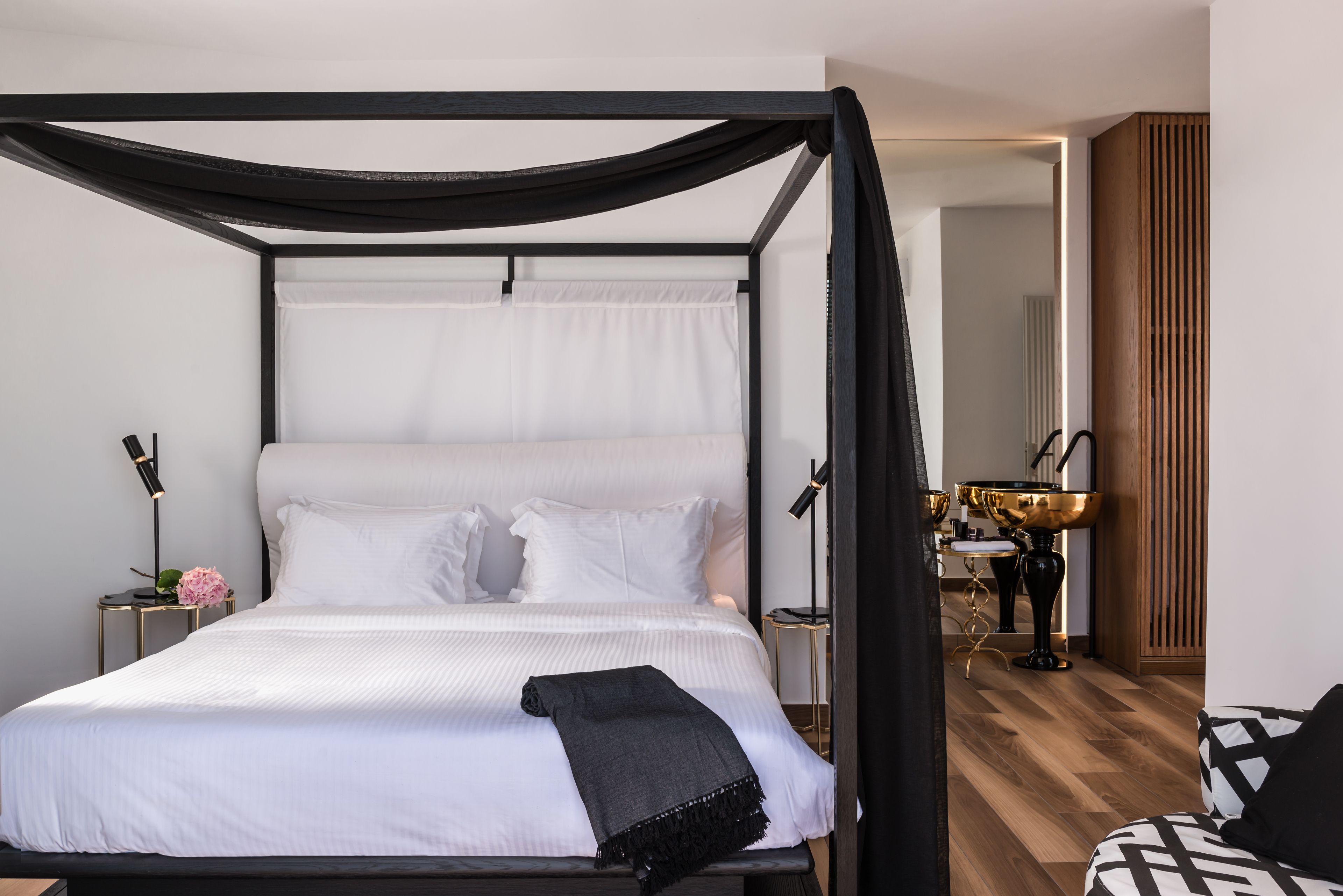A four-poster canopy bed with white linens and a black throw blanket.