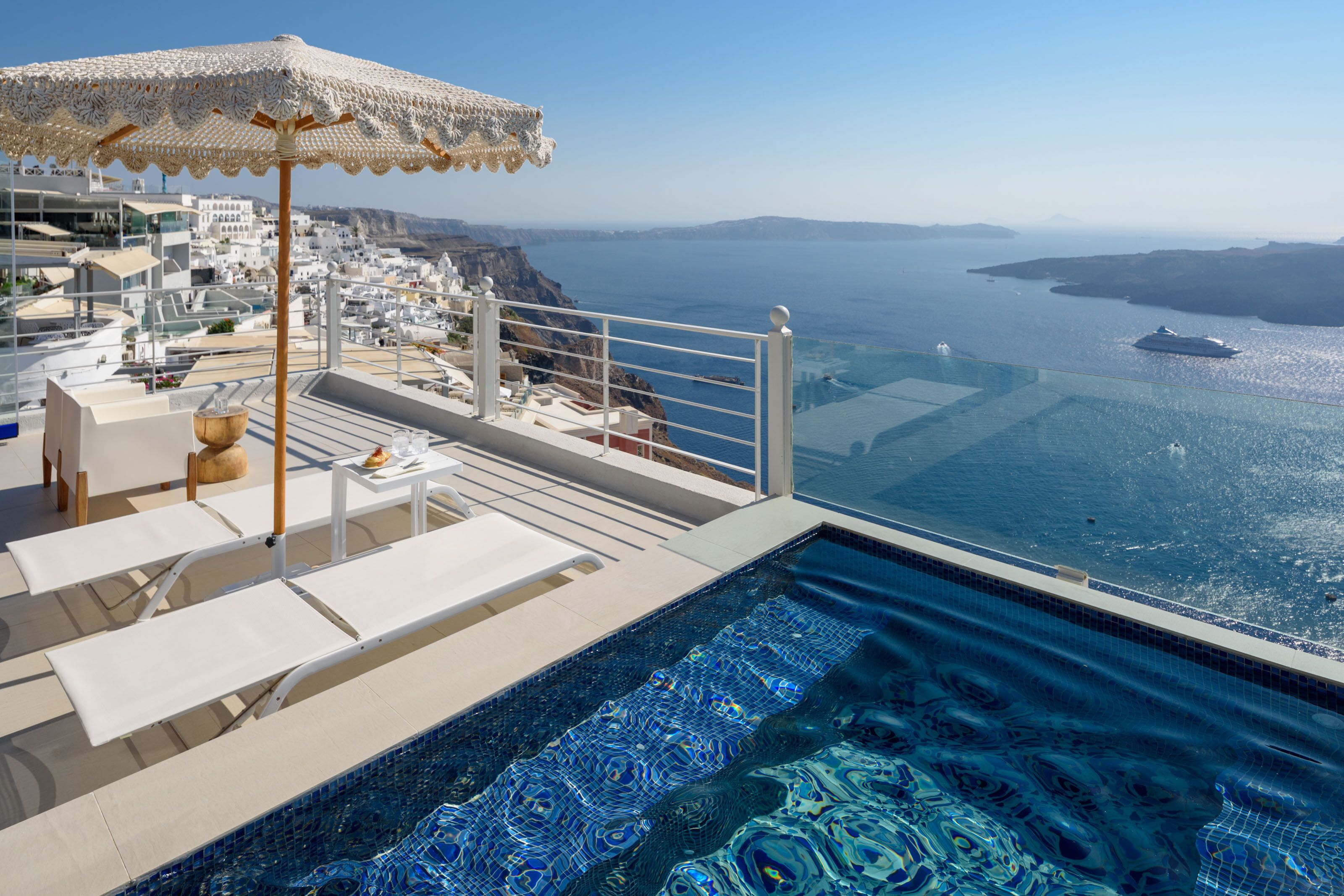 A luxurious infinity pool with a view of the sea and a white umbrella.