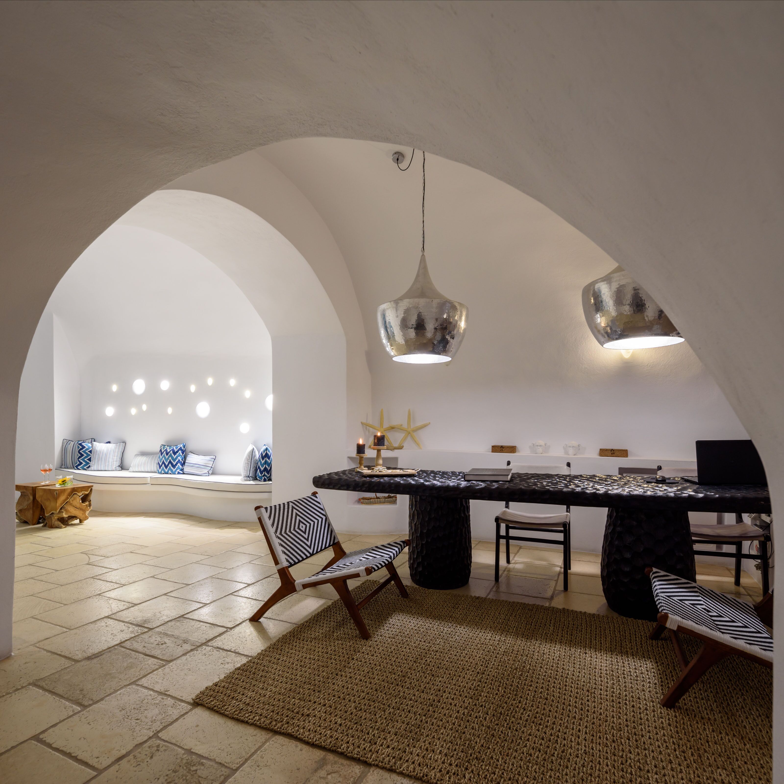 Une cuisine moderne dotée d’un îlot central, d’arcs blancs et de luminaires suspendus.