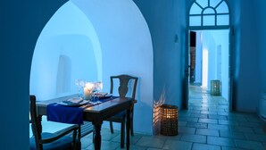 A dining area with a table set for two, a candle, and a wicker basket. - Nefeles Luxury Suites (Santorini)