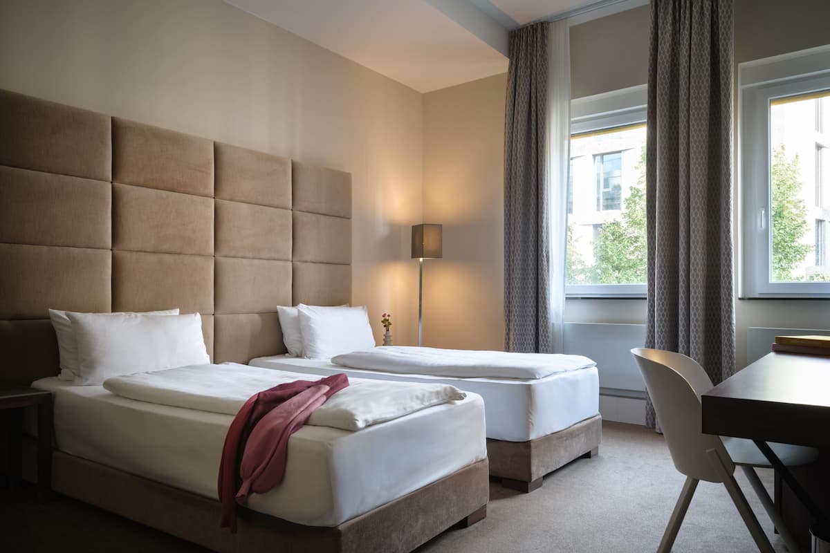 Ett hotellrum med två sängar, ett skrivbord och en stol.