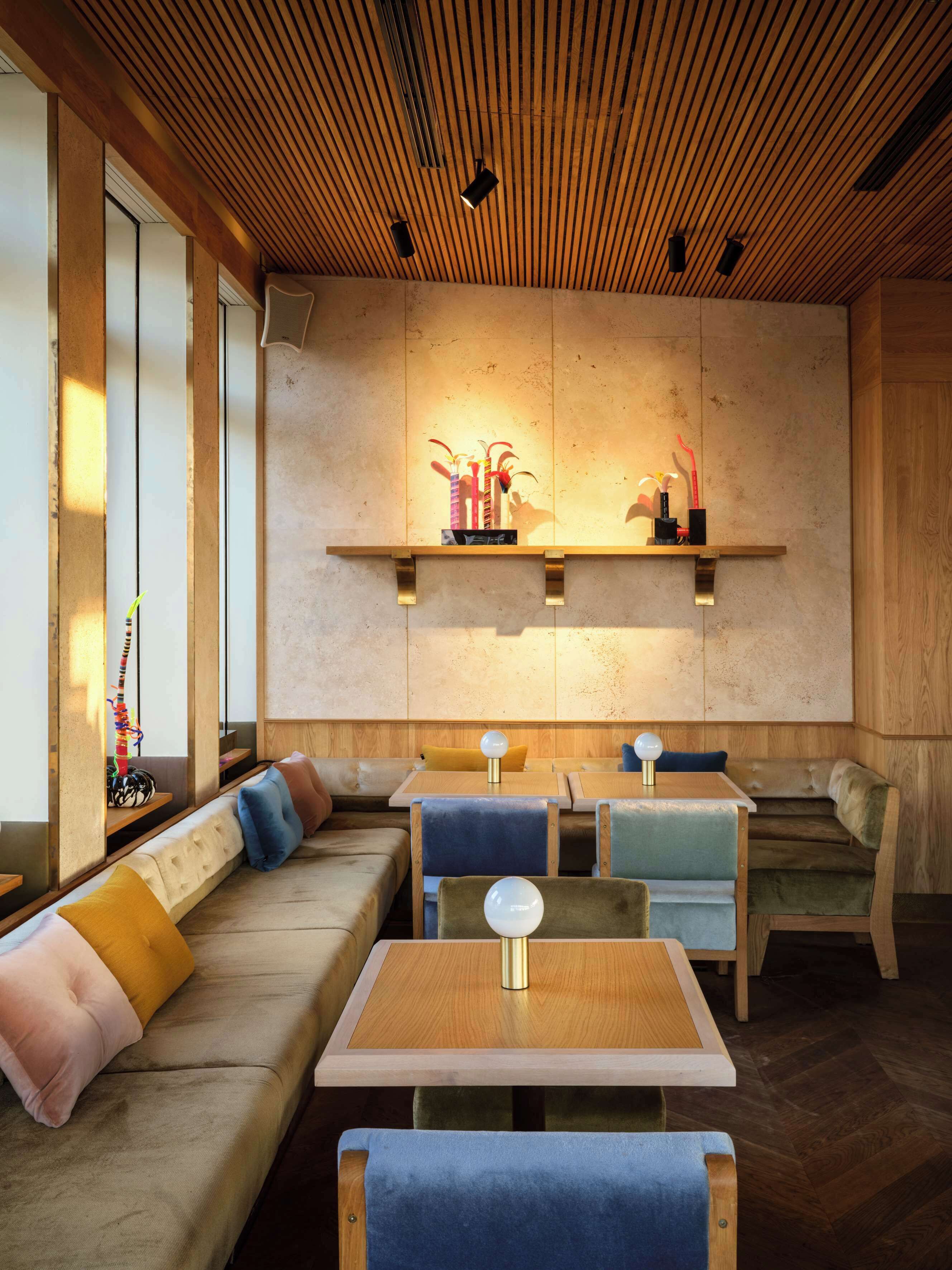 A modern interior with a wooden ceiling, built-in seating, and pendant lighting.