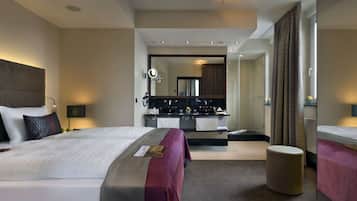 A modern hotel room with a large bed, a separate bathroom with a mirror, and a small seating area.