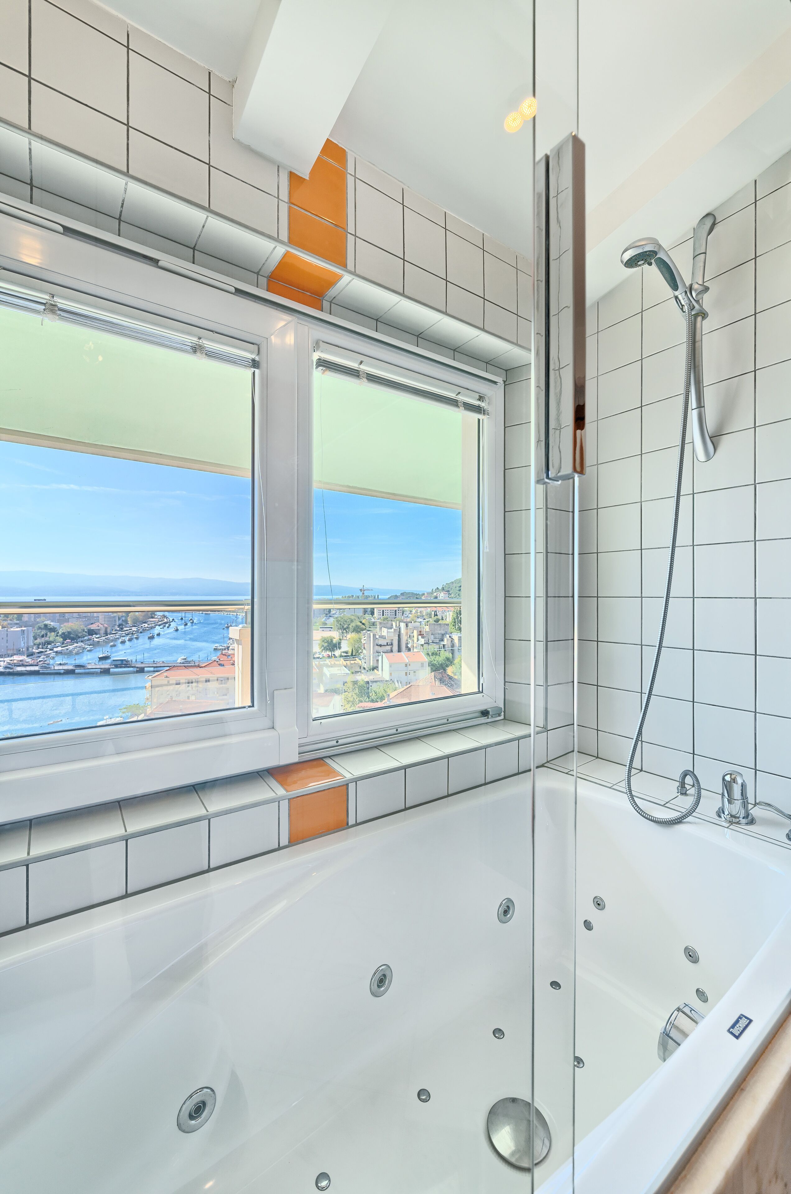 A modern bathroom with a large bathtub, a shower, and a window offering a city view.