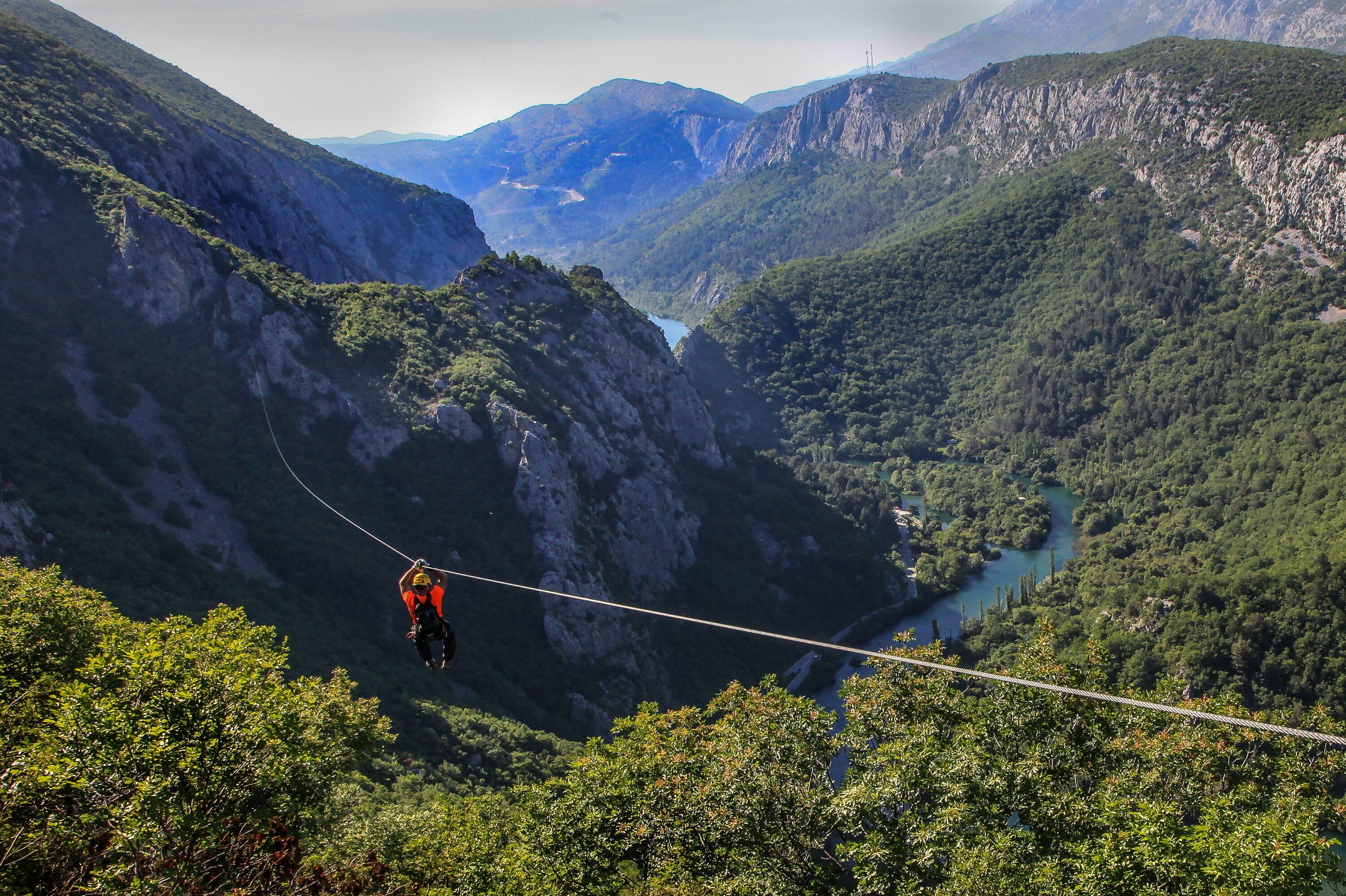 A person bungee jumping from a high cliff with a river below.
